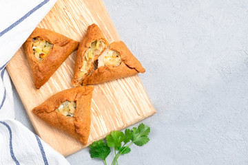 Tatar traditional triangular pastry with potatoes, onion, meat on neutral background. Image with copy space, top view © Elena