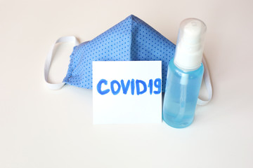 Home made cloth cotton face mask and antibacterial gel sanitizer to prevent coronavirus Covid 19. Hand made face mask blue color on white background.