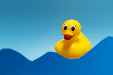 Children's bath rubber yellow duck in the waves. Swimming concept. Minimal idea. Copy space. Place for text and design. Abstract photo