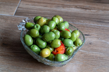 Green marinated olives with oregano, garlic, red pepper, herbs and spices on a wooden background. Recipe for marinated olives