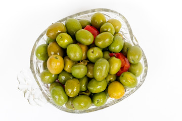 Marinated olives in small transparent bowl. On white background. Pickled green olives