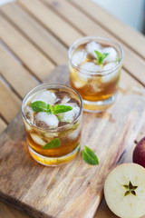 Apple juice with ice and garnish on wooden background