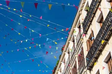 Tuinposter Street full of colored pennants crossing the street of the city center on a sunny day, Madrid, Spain. © Mario