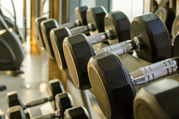 Fototapeta na wymiar Close up dumbbells on a dumbbells rack in the gym, in the evening