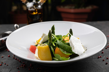 Green salad with cheese and grapefruit on a dark background