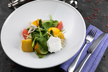 Green salad with cheese and grapefruit on a dark background