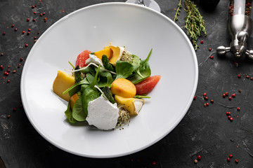 Green salad with cheese and grapefruit on a dark background
