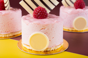 Raspberry vanilla and white chocolate mousse dessert with logo space isolated on yellow and brown.