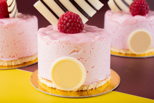 Raspberry vanilla and white chocolate mousse dessert with logo space isolated on yellow and brown.