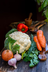 Vegetables - cauliflower carrots garlic onions on a wooden rustic table.