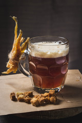 Mug of beer. Dried fish is attached to it. Near leat crackers