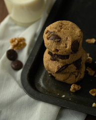 oatmeal cookies with peanut butter and chocolate sparks and a glass of milk on a rusty metal baking sheet