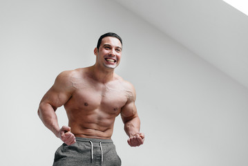 A sporty guy screams in rage against a white background. Anger. Threat