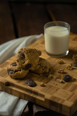 oatmeal cookies with peanut butter and chocolate sparks with a glass of milk on a wooden board