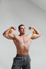 Sporty sexy guy posing on a white background with bright fruits. Diet. Healthy diet