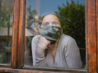 A girl quarantined at home looking outside because of covid19.