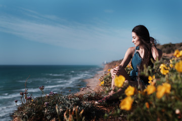 Young cute girl sitting on the edge of the cliff enjoying the view