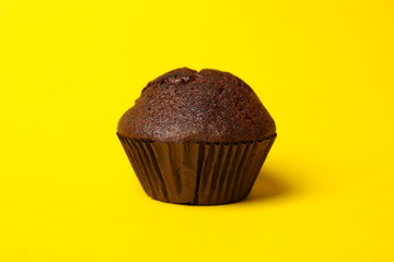 Tasty chocolate muffin on yellow background, close up