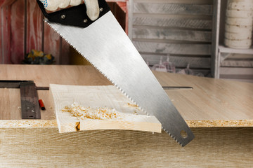 Carpenter sawing a board with a hand wood saw