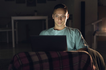 A lonely man sits at home at night and works online.
