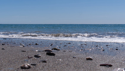Bright sunny afternoon at the beach with shinny stones and beautiful blue ocean