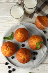 Composition with muffins and milk on white wooden background