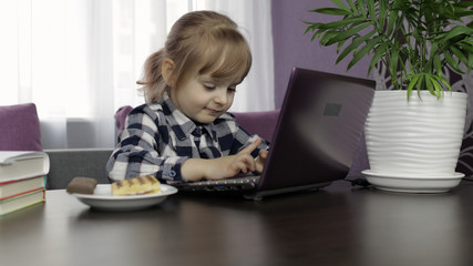 Girl doing lessons at home using digital laptop computer. Distance education