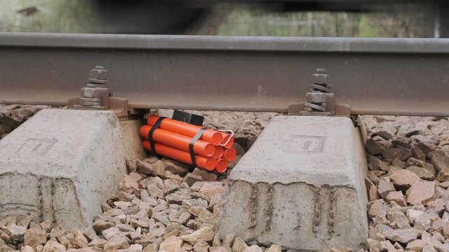 time bomb lies on railway on background of passing train on stones under rail between sleepers. concept of terrorist act.