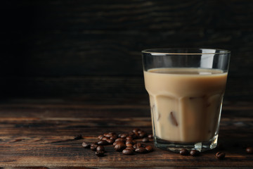 Glass of ice coffee on wooden background. Coffee seeds