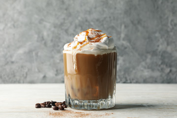Glass of ice coffee with poured cream on wooden table