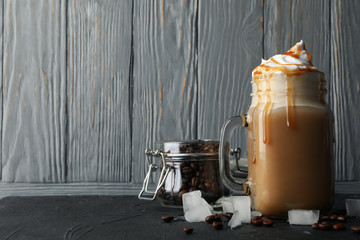 Iced coffee with poured cream on gray wooden background