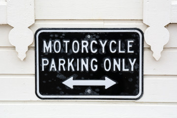 Motorcycle parking only sign against the background of a white wooden wall