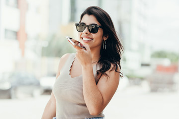 Young woman using cellphone voice command outdoors in the city