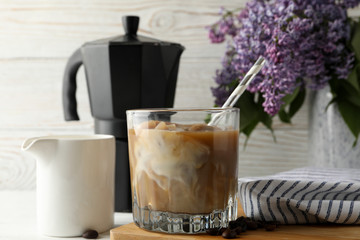 Composition with ice coffee and flowers on white wooden background