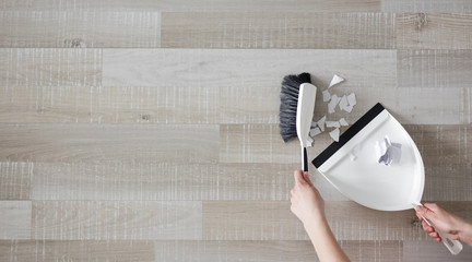 top view of male hands cleaning ripped pieces of paper with scoop and brush - copy space over wooden floor