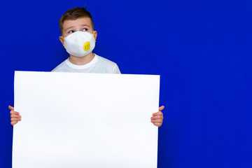 Close up Portrait of caucasian boy in a protective mask respirator holds a blank sheet of paper on...