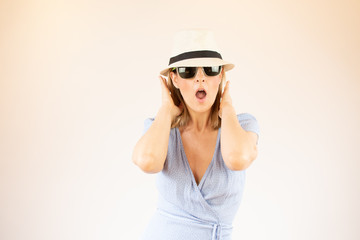 Naklejka premium Young woman wearing hat and glasses making surprised gesture on vacation