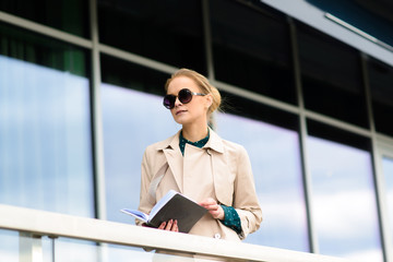 Happy beautiful businesswoman with sunglasses, phone, laptop, cup of coffee in the city streets.