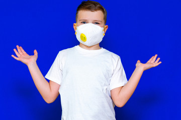 Kid wearing face respirator during corona virus and flu outbreak. The boy spreads his arms out to the sides. Surgical masks for coronavirus prevention. Bright blue background.Copy space,banner.