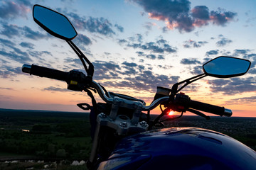 View over the handlebars of motorcycle  at sunset time.Traveling on bike, freedom concept.