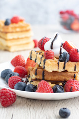 Belgian waffles with fresh fruit on wooden background