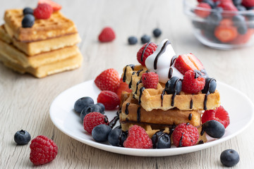 Belgian waffles with fresh fruit on wooden background