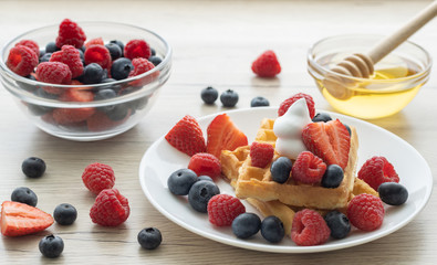 Belgian waffles with fresh fruit on wooden background