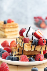Belgian waffles with fresh fruit on wooden background