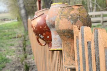 close up of wooden fence with old clay pots and jugs