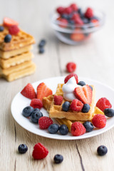 Belgian waffles with fresh fruit on wooden background