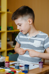 A cute little boy is playing and painting in his room. Recreation and entertainment. Stay at home