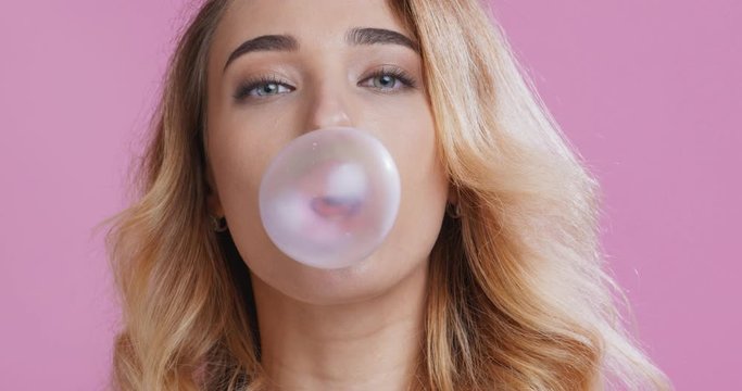 Young girl chewing bubble gum, making balloon