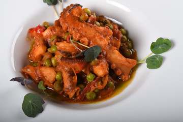 Polpo alla diavola. Octopus with tomato sauce served in a white plate, closeup view.