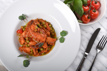 Polpo alla diavola. Octopus with tomato sauce served in a white plate, closeup view.